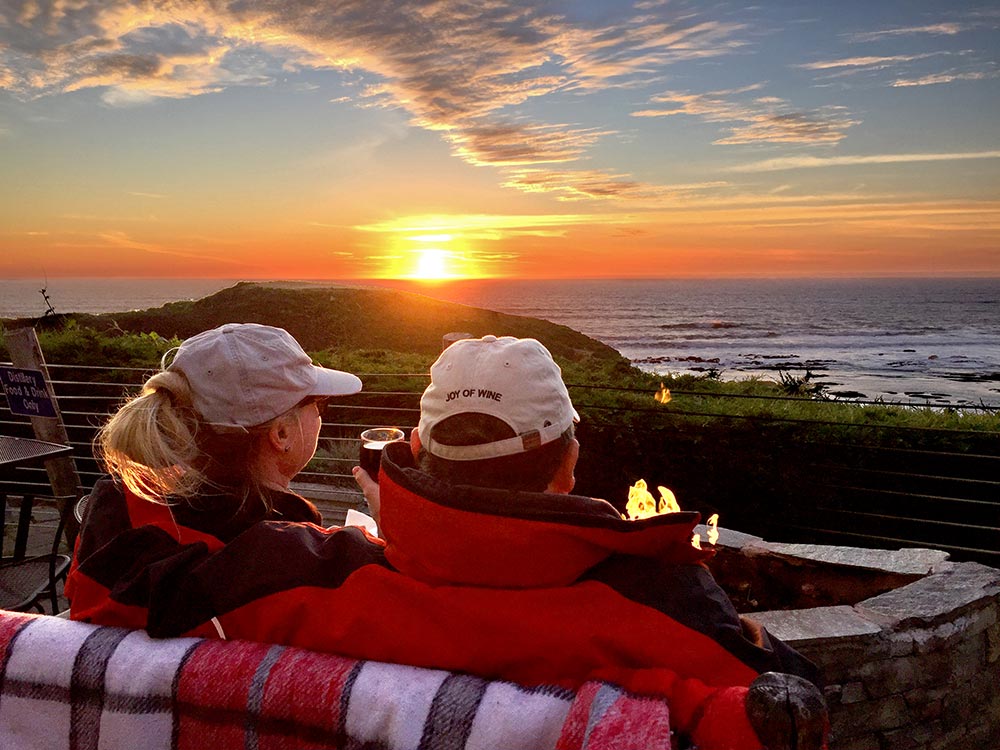 couple sitting by patio firepit watching sunset